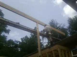 Carpenter setting a ridge beam over a new addition frame — Ice Dam Removal by Roofing Brothers in Volant