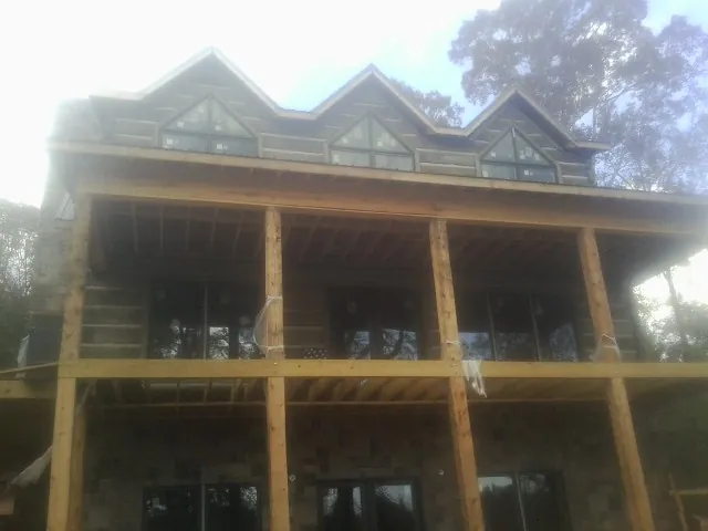 Dormers and porch framing on a large log home under construction — Roof Coating work by our crew in Volant