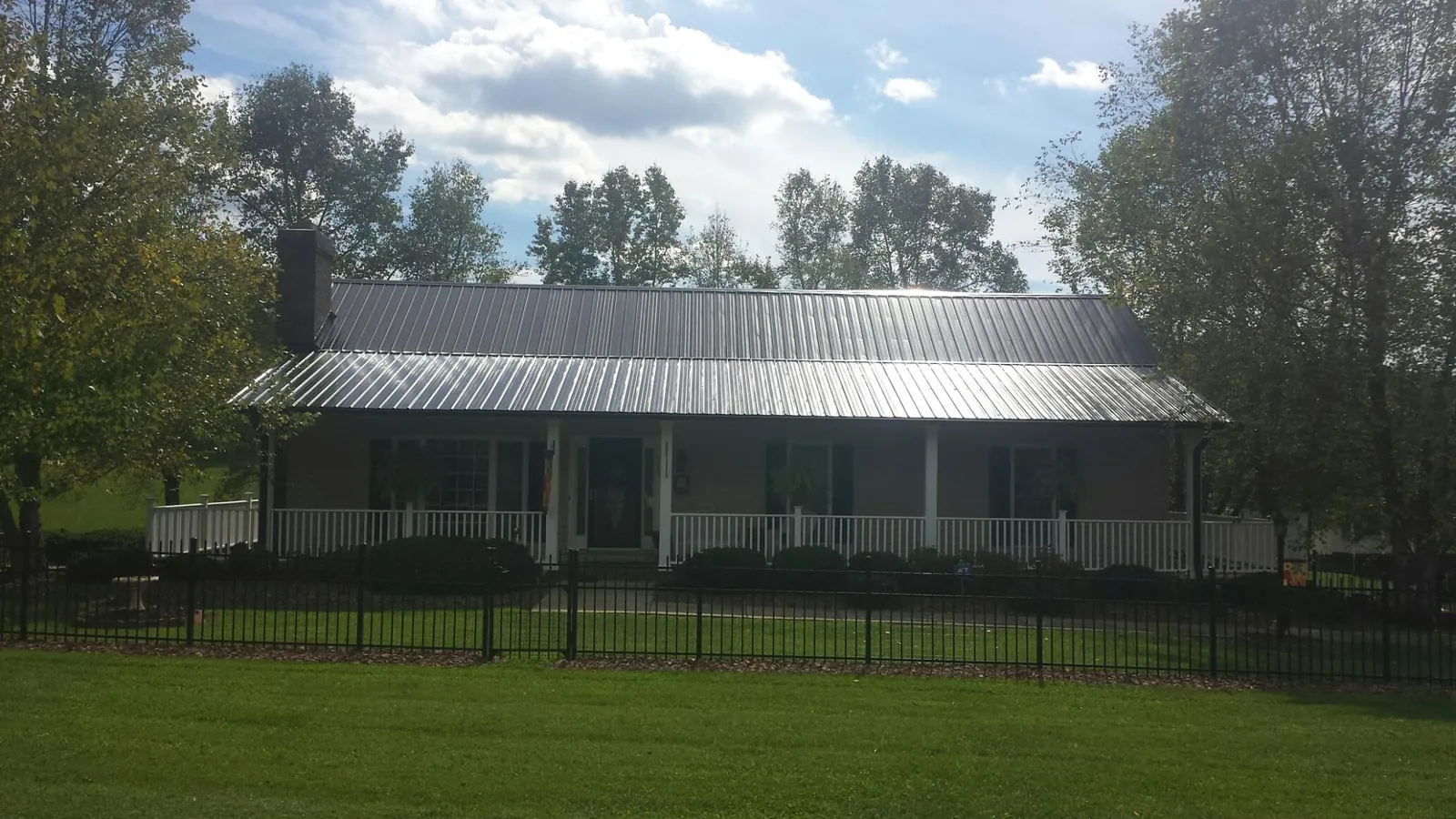 Gray metal roof on a brick ranch with a full width front porch — Gutter Guard Installation work by our crew in Volant