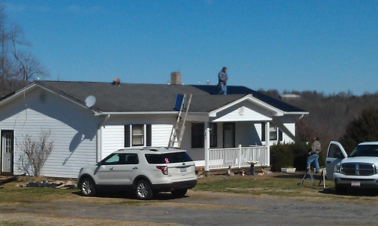 Roofers stripping shingles from a white ranch house roof in Volant