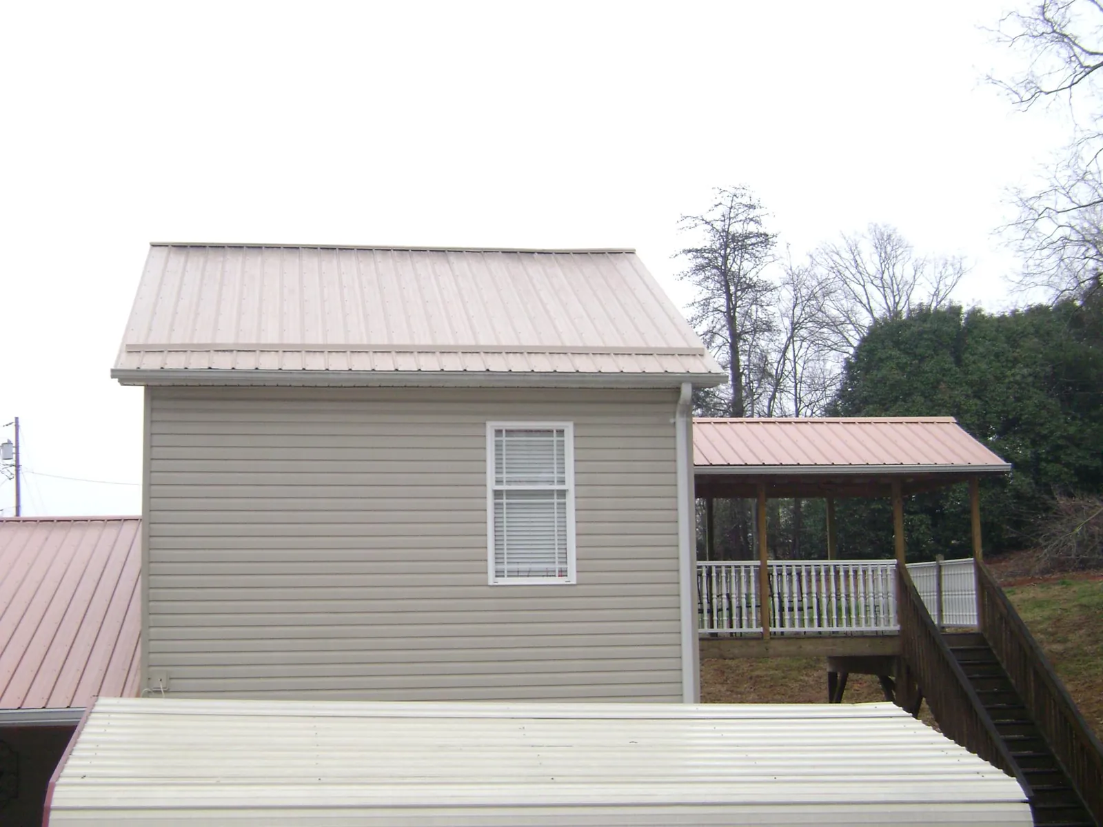 Tan metal roofs on a two story addition and attached porch, from a Roof Replacement job in Volant
