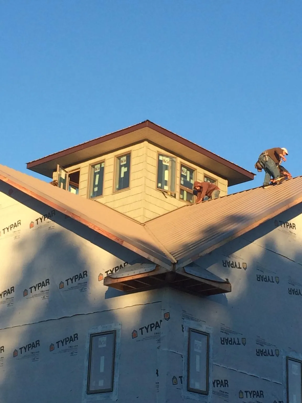 Roofers working around a rooftop cupola on a new metal roof at sunset — Roof Waterproofing in Volant by Roofing Brothers
